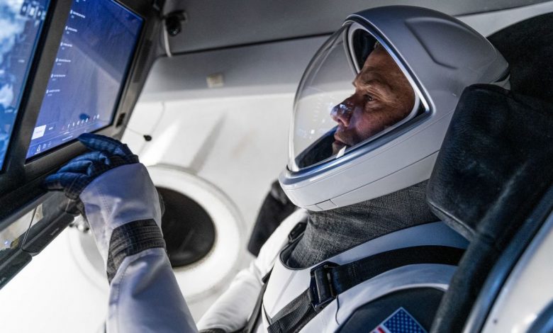 nasa astronaut reaching for display panel inside of a spacesuit